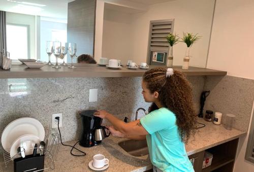 Una joven está parada en un fregadero de la cocina en Midas 712 - Lazer ou Negócio - WI-FI 200 MB e Netflix, en Río de Janeiro