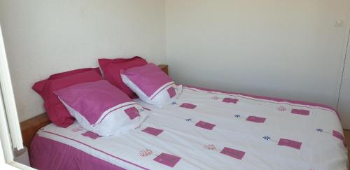 a bed with pink and white sheets and pillows at L'Océnoa in Mimizan-Plage