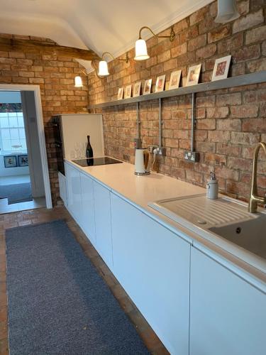 cocina con fregadero y pared de ladrillo en The Green House en Horncastle