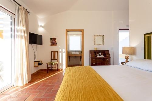 a bedroom with a large white bed and a desk at Cerro da Campaniça in Santiago do Cacém