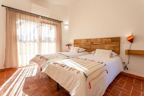 two twin beds in a room with a window at Cerro da Campaniça in Santiago do Cacém