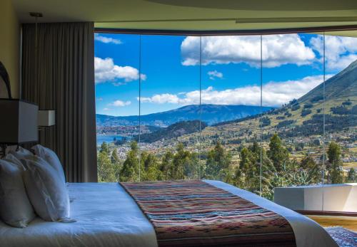 a bedroom with a large window with a mountain view at Hotel Medina Del Lago in Otavalo