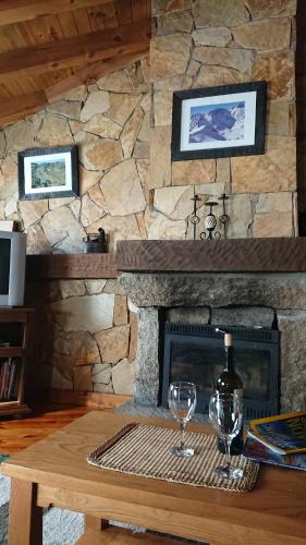 a stone fireplace with two wine glasses on a table at Artesano II in Navarredonda de Gredos