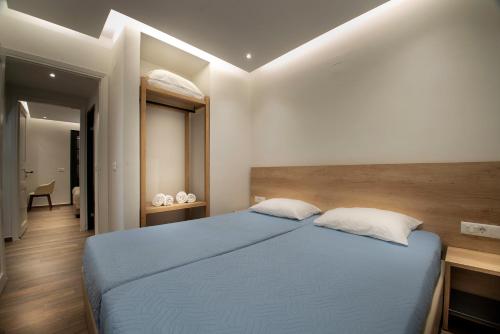 a bedroom with a blue bed with two pillows at Villa Margarita Suites in Hersonissos