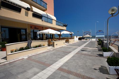 a building with tables and umbrellas next to the beach at Hotel Baia in Rimini