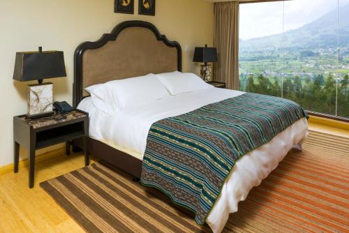 a bedroom with a large bed and a large window at Hotel Medina Del Lago in Otavalo