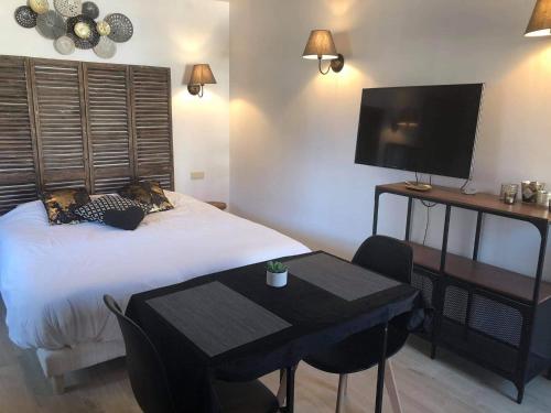 a bedroom with a bed and a table and a television at Le petit studio de l'espace bien être in Libin