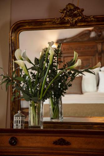 two vases with flowers on a table in front of a mirror at Hotel Palazzo Guadagni in Florence