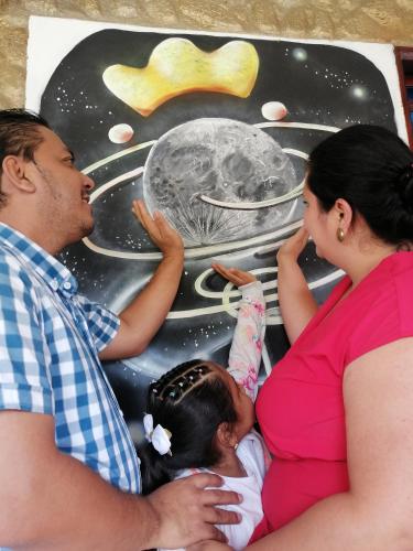a man and a woman and a baby sitting next to a painting at Cabañas Guacari San Agustín huila in San Agustín