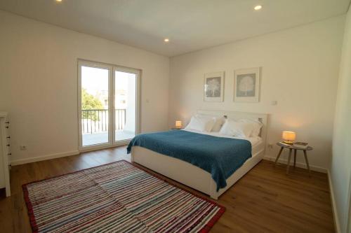 a bedroom with a bed and a large window at Casa do Coreto, Paço, São Bartolomeu dos Galegos in Paço