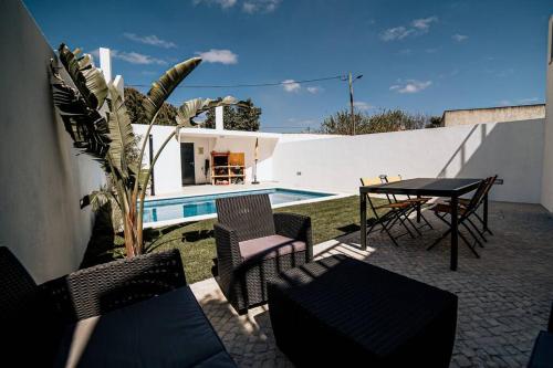 a patio with a table and chairs next to a pool at Casa do Coreto, Paço, São Bartolomeu dos Galegos in Paço