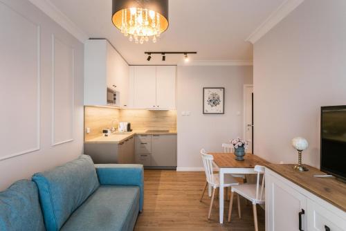 a living room with a blue couch and a kitchen at Papillon Apartamenty Gdańsk in Gdańsk