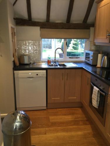 a kitchen with a sink and a stove top oven at The Byre at Heartwood in Ticehurst