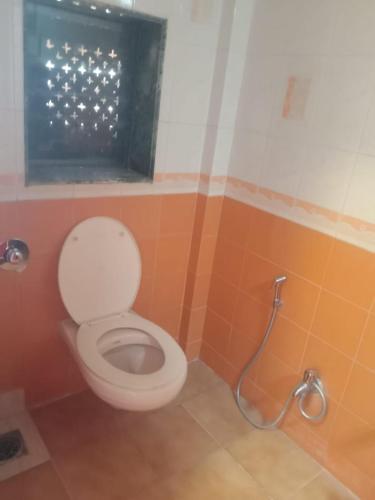 a bathroom with a toilet with a window at Kuber's Residency in Mahad