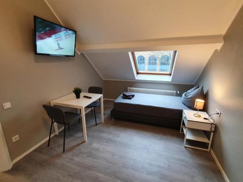 Kleines Zimmer mit einem Bett, einem Tisch und einem TV. in der Unterkunft Stadt Apartments Solingen in Solingen