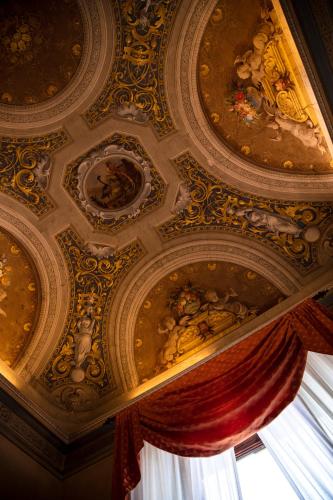 a ceiling with paintings on it with a window at Hotel Palazzo Guadagni in Florence
