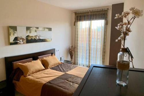 a bedroom with a bed with a table and a vase with flowers at Apartamento Miramar . Amplitud y Comodidad in Almazora