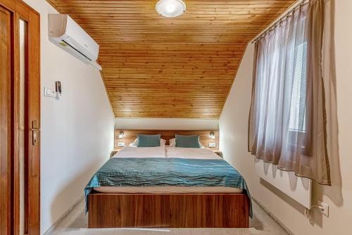 Ce petit lit se trouve dans une petite chambre dotée d'un plafond en bois. dans l'établissement Pósteleki Vendégház-Nyugalom Szigetei, à Gyula