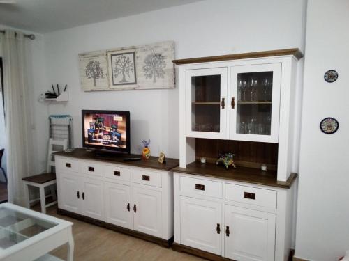 salon z białymi szafkami i telewizorem w obiekcie Primera linea de playa "Barrosamar" w mieście Chiclana de la Frontera