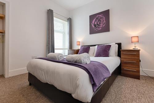 a bedroom with a large bed with purple pillows at Work Stay - Parking - 4BRM - Spacious in Swansea