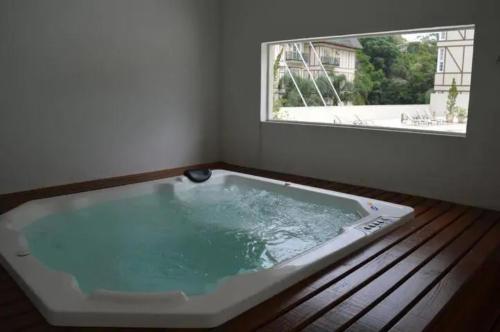 a bath tub in a room with a window at Charmoso Flat em Itaipava, 509 Mangabeiras. in Petrópolis