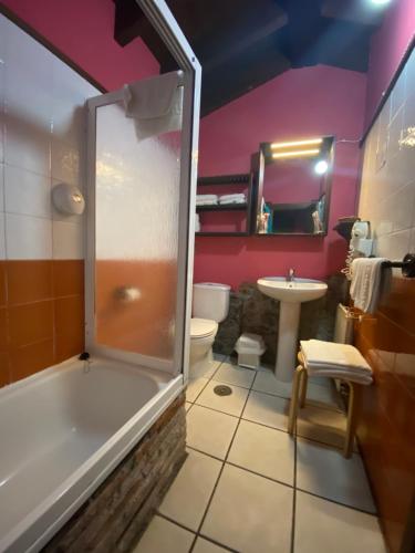 a bathroom with a tub and a toilet and a sink at Hotel Rural Los Texos in La Riera