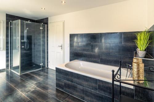 y baño con bañera y ducha acristalada. en Green Valley Lounge Apartment, en Weibern