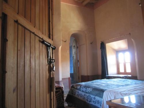 a bedroom with a bed and a large wooden door at Kasbah Ait Kassi in Boumalne