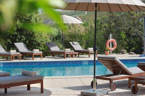 a swimming pool with lounge chairs and an umbrella at Quinta da Luz - A Luxury Boutique B&B in Silves