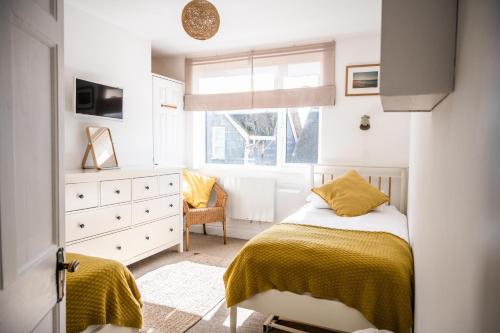 a bedroom with a bed and a dresser and a window at Flat 1 Teneriffe in Lyme Regis