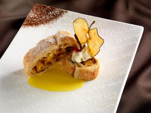 a sandwich on a white plate with yellow sauce at Hotel Garden in Moena