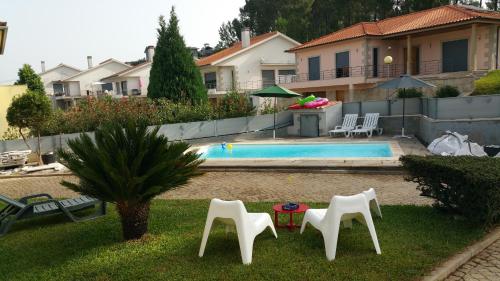 a yard with three white chairs and a pool at Casa de Água levada in Picarouba