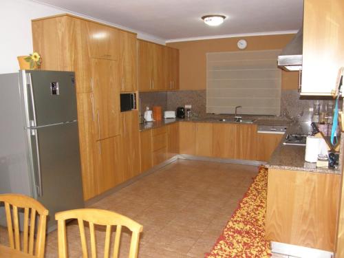 a kitchen with wooden cabinets and a stainless steel refrigerator at Casa de Água levada in Picarouba