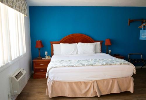 a bedroom with a large bed with a blue wall at Daytona Dream Inn By AmeriVu in Daytona Beach
