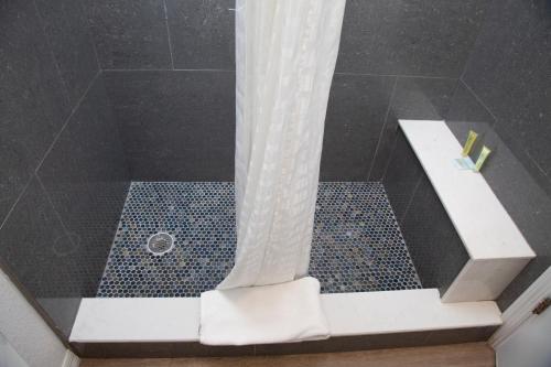 a shower with a white shower curtain in a bathroom at Daytona Dream Inn By AmeriVu in Daytona Beach