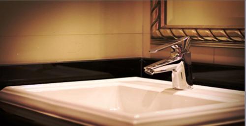 a bathroom sink with a silver faucet and a mirror at Gulliver's Tavern Hotel in Bangkok