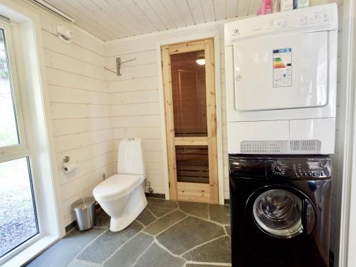 a small bathroom with a toilet and a washing machine at Eagle Bay Lofoten in Gravdal