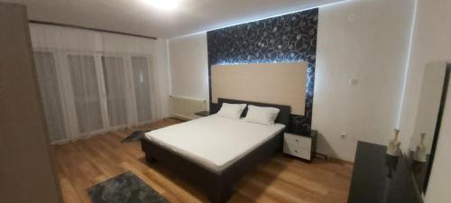 um quarto com uma cama branca e uma parede azul em Apartman EXCLUZIV em Prijedor