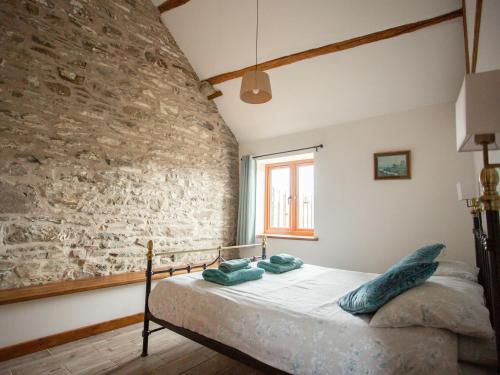 Bett in einem Zimmer mit einer Steinmauer in der Unterkunft 1 Beacon View Barn in Felindre