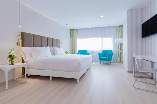 a white bedroom with a white bed and a tv at NH Puebla FINSA in Puebla