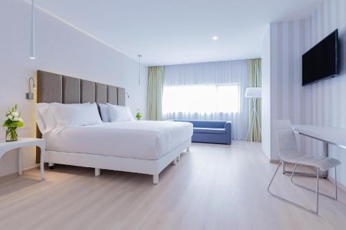 a white bedroom with a white bed and a television at NH Puebla FINSA in Puebla