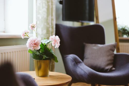 a vase of pink flowers on a table next to two chairs at Hotel Benevilla in Alūksne