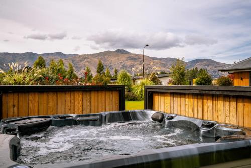 una vasca idromassaggio in un cortile con montagne sullo sfondo di Erskine Place - Lake Hawea Holiday Home a Lake Hāwea