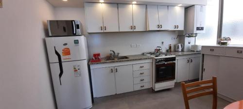 a kitchen with white cabinets and a white refrigerator at ALMAR III Sólo para familias in Mar del Plata