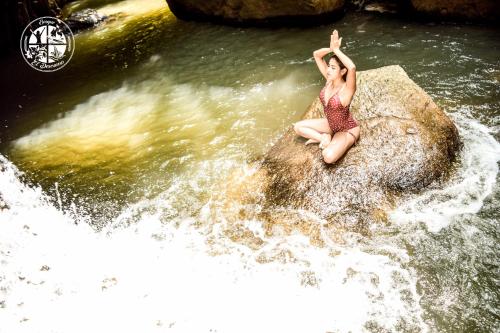 a woman sitting on a rock in a river at BOSQUE EL DESCANSO in Jamundí