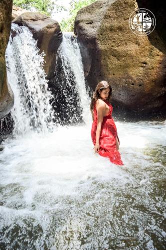 a woman in a red dress standing in front of a waterfall at BOSQUE EL DESCANSO in Jamundí