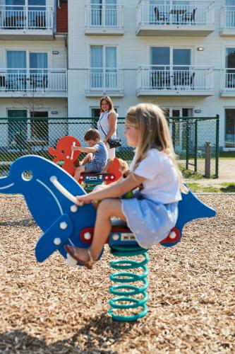 a young girl sitting on a ride on a playground at ibis Styles Nieuwpoort in Nieuwpoort