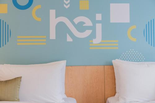 a bed with white pillows in front of a wall at Hej Taipei in Taipei