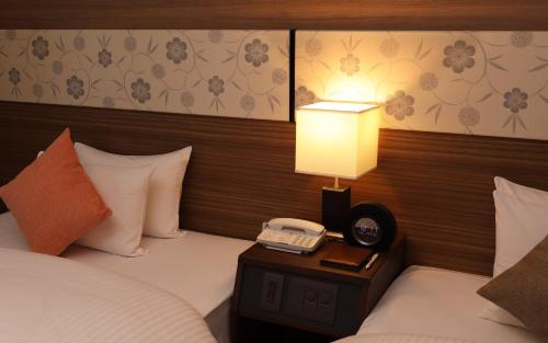a hotel room with two beds and a phone on a table at SHIROYAMA HOTEL kagoshima in Kagoshima