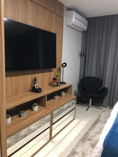 a living room with a large television on a wooden wall at Charmoso Flat em Itaipava, 509 Mangabeiras. in Petrópolis